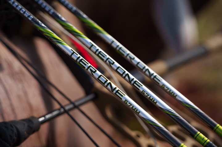 Close-up of three Tier One arrows with black, silver, and green accents, featuring the text &
